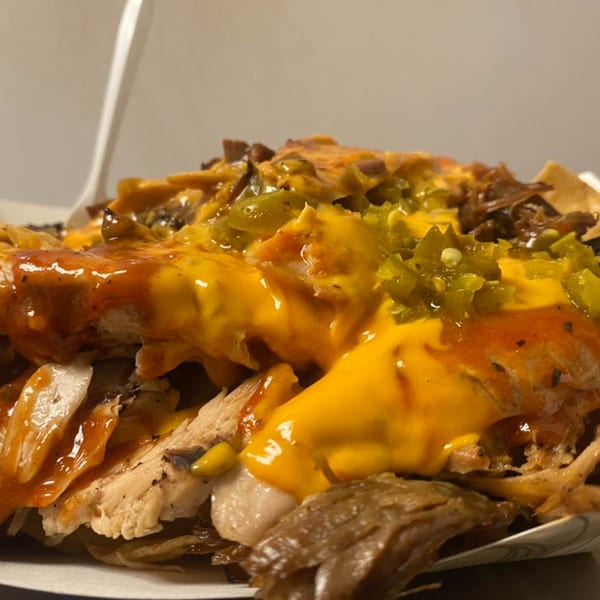 Close-up of Pappies Smokehouse & Lunch Box BBQ nachos with cheese, sauce, and jalapeños.