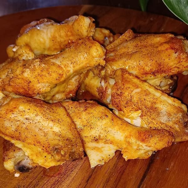 Close-up of golden-brown, seasoned chicken wings on a wooden platter, ready to be served.