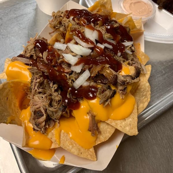 Pappies Smokehouse & Lunch Box BBQ nachos with pulled pork, cheese sauce, BBQ sauce, and onions.